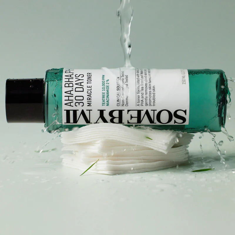 Koreansk hudvårdsprodukt på grå bakgrund, liggande på bomullspads där vatten rinner över produkten: Some By Mi AHA.BHA.PHA 30 Days Miracle Toner för exfoliering, rengöring av porer, förbättrad hudtextur och lugnande av känslig hud med Tea Tree-extrakt.